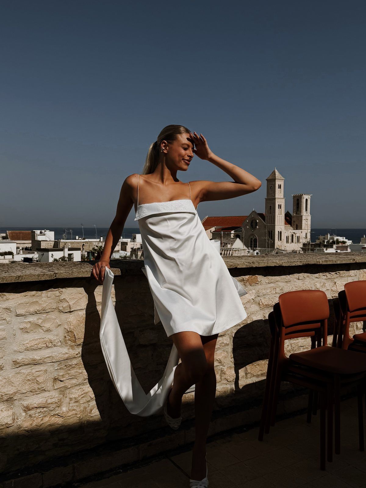 Abito corto in mikado con lungo strascico su una terrazza di Giovinazzo